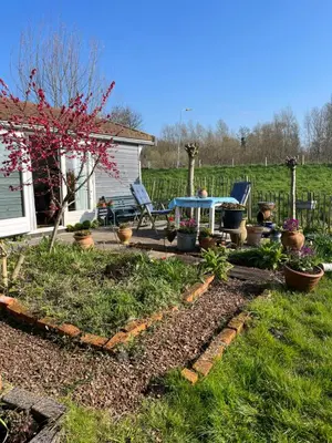 a garden with a table and chairs in a yard at Rosa's zonnige huisje bij duinen bos en strand in Warmenhuizen