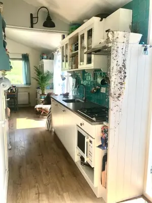 a kitchen with white cabinets and a stove top oven at Rosa's zonnige huisje bij duinen bos en strand in Warmenhuizen