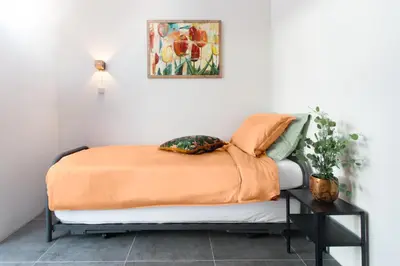 a bed with an orange comforter and pillows on it at Huis met de krul in Amsterdam