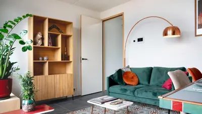 a living room with a green couch and a table at Huis met de krul in Amsterdam