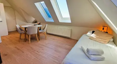 a bedroom with a bed and a table with chairs at Pension Zandvoort aan Zee in Zandvoort