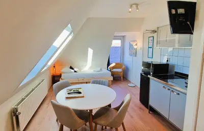 a kitchen and a living room with a table and chairs at Pension Zandvoort aan Zee in Zandvoort