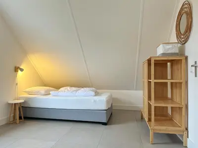 a small bedroom with a bed and a shelf at Bungalow 57 op Recreatiepark De Wielen in Sint Maarten