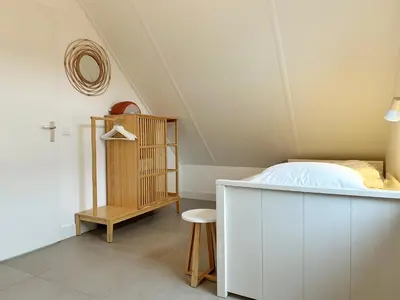 a bedroom with a bed and a table and a stool at Bungalow 57 op Recreatiepark De Wielen in Sint Maarten