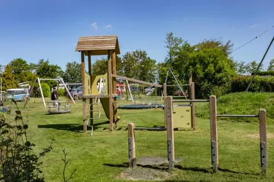 a park with a playground with a swing set at Bungalow 57 op Recreatiepark De Wielen in Sint Maarten