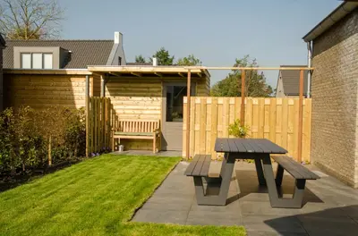 a picnic table and a bench in a garden at Bungalow 70 op Recreatiepark De Wielen in Sint Maarten
