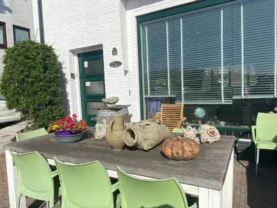 a table with green chairs and vases on a patio at Appartement Twins in Wijk aan Zee
