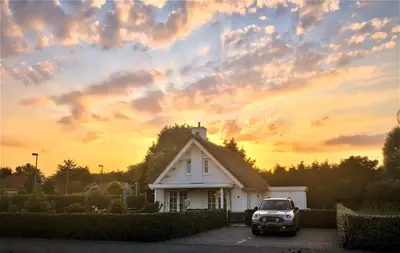 a truck parked in front of a house with a sunset at Golden Wellness Villa Noordwijk in Noordwijk
