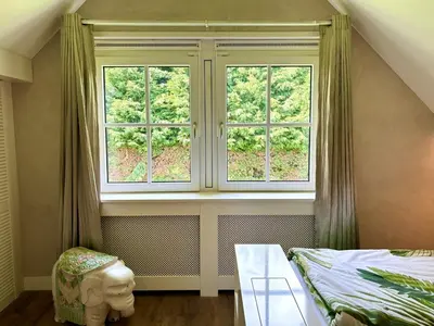 a bedroom with two windows and a bed and a table at Golden Wellness Villa Noordwijk in Noordwijk