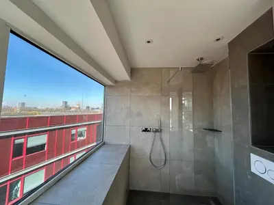 a bathroom with a shower and a large window at XO Hotels Blue Tower in Amsterdam