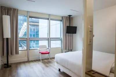 a hotel room with a bed and a chair and window at Qbic Amsterdam WTC in Amsterdam