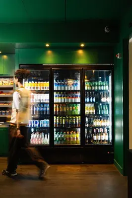 a man is walking past a refrigerator full of drinks at Qbic Amsterdam WTC in Amsterdam