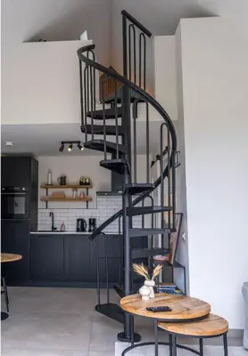 a black spiral staircase in a kitchen with a table at Veldt's huisje in Limmen