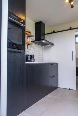 a kitchen with a black refrigerator and a microwave at Veldt's huisje in Limmen