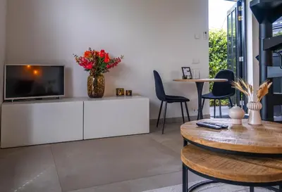 a living room with a tv on a white cabinet at Veldt's huisje in Limmen