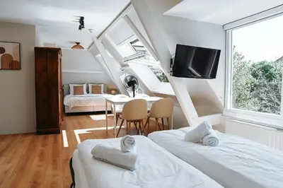 two beds in a room with a table and a tv at High Street Apartments in Zandvoort