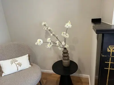 a vase with white flowers on a table next to a chair at High Street Apartments in Zandvoort