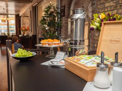 a counter with a table with food and fruit on it at Heeren van Noortwyck in Noordwijk aan Zee