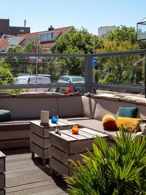 a patio with couches and tables on a balcony at Heeren van Noortwyck in Noordwijk aan Zee