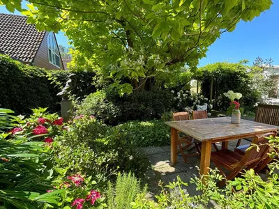 a wooden table and chairs in a garden at Holiday Home near Noordwijk Beach in Noordwijkerhout