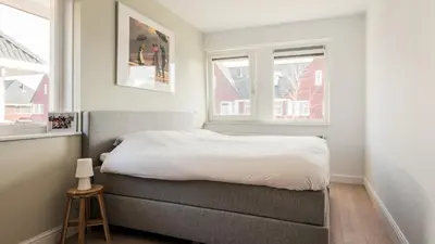 a small bedroom with a bed and two windows at Casa Jill in Bergen