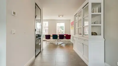 a hallway with white cabinets and blue chairs at Casa Jill in Bergen