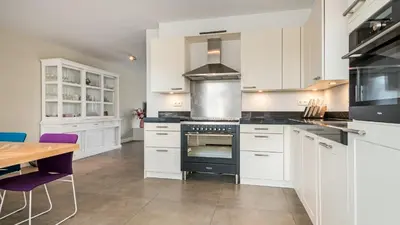 a kitchen with white cabinets and a black oven at Casa Jill in Bergen