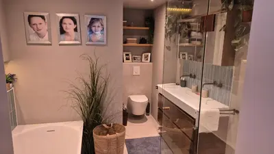 a bathroom with two sinks and a toilet and pictures on the wall at Bungalow 15 op Recreatiepark De Wielen in Sint Maarten