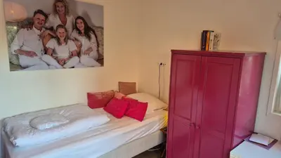 a bedroom with a red cabinet and a bed at Bungalow 15 op Recreatiepark De Wielen in Sint Maarten