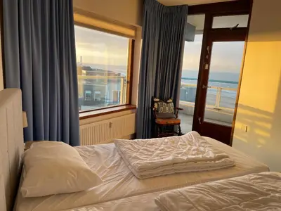 a bedroom with a bed and a large window at Sterflat 207 in Egmond aan Zee