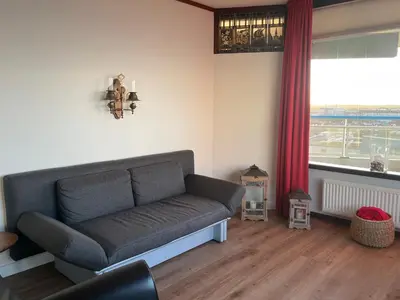 a living room with a couch and a window at Sterflat 207 in Egmond aan Zee
