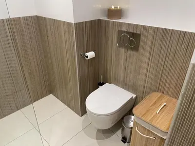 a bathroom with a toilet and a wooden wall at Sterflat 207 in Egmond aan Zee