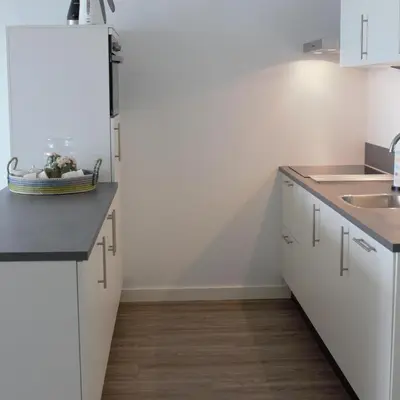 a white kitchen with a sink and a refrigerator at Sterflat 219 in Egmond aan Zee