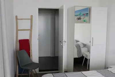 a bedroom with a mirror and a bed and a chair at Sterflat 219 in Egmond aan Zee