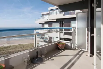 a balcony with a view of the beach and the ocean at Sterflat 223 in Egmond aan Zee