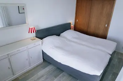 a small bedroom with a bed and a mirror at Sterflat 227 in Egmond aan Zee