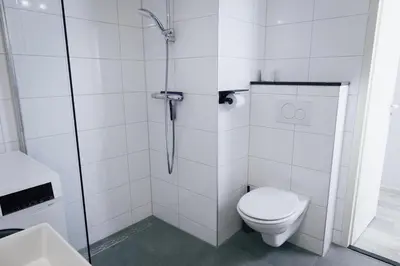 a white bathroom with a toilet and a shower at Sterflat 227 in Egmond aan Zee