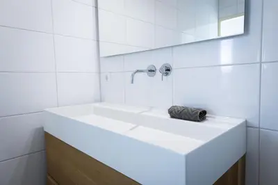 a white bathroom with a sink and a mirror at Sterflat 227 in Egmond aan Zee