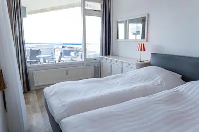 a bedroom with a bed and a large window at Sterflat 227 in Egmond aan Zee