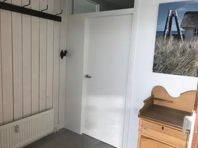 a white door in a room with a wooden cabinet at Sterflat 241 in Egmond aan Zee