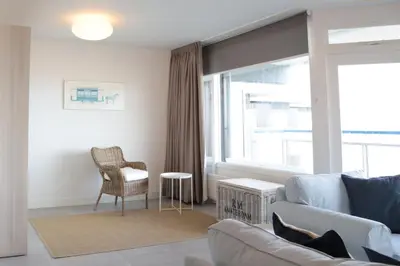 a living room with a couch and a chair and a window at Sterflat 241 in Egmond aan Zee