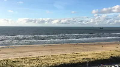 a beach with people and a boat in the water at Sterflat 241 in Egmond aan Zee
