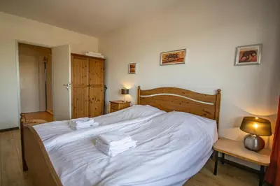 a bedroom with a white bed with towels on it at Sterflat 249 in Egmond aan Zee