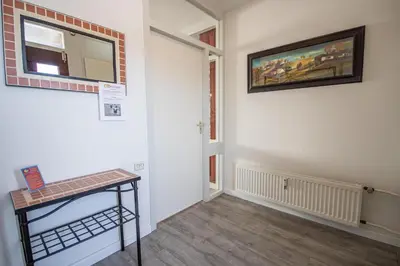 a hallway with a table and a painting on the wall at Sterflat 249 in Egmond aan Zee
