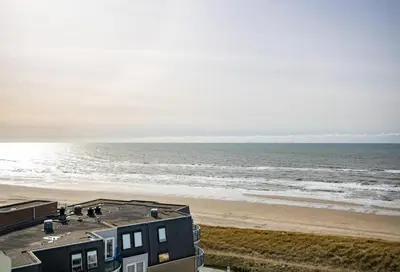 a view of a beach with a building and the ocean at Sterflat 249 in Egmond aan Zee