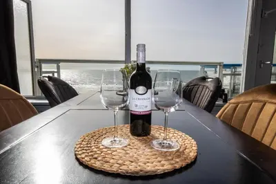 a bottle of wine and two glasses on a table at Sterflat 249 in Egmond aan Zee