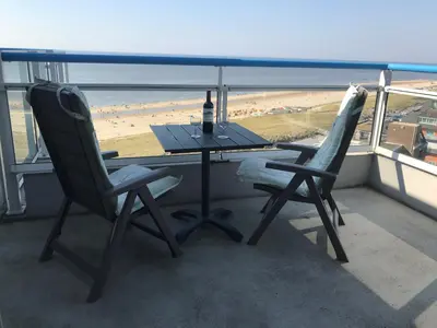 a table with a bottle of wine and two chairs at Sterflat 259 in Egmond aan Zee