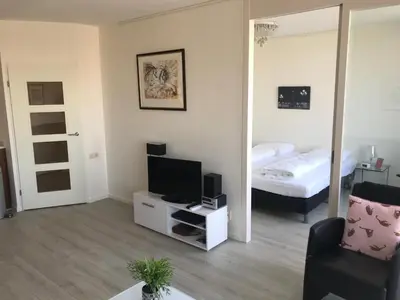 a living room with a tv and a mirror at Sterflat 259 in Egmond aan Zee