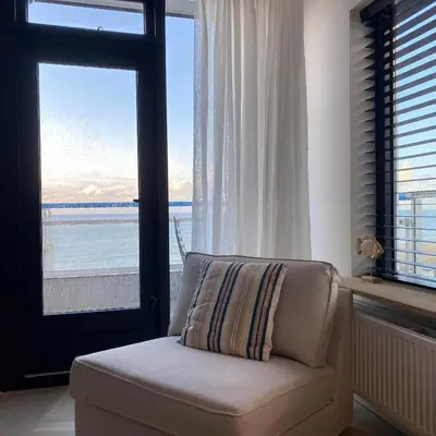 a living room with a chair and a large window at Sterflat 261 in Egmond aan Zee