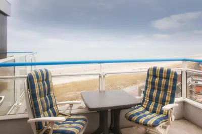 a table and chairs on a balcony with a view of the beach at Sterflat 261 in Egmond aan Zee